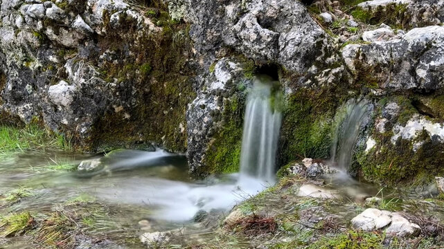 Clean, healthy, drinkable natural water gushing from underground between the rocks.