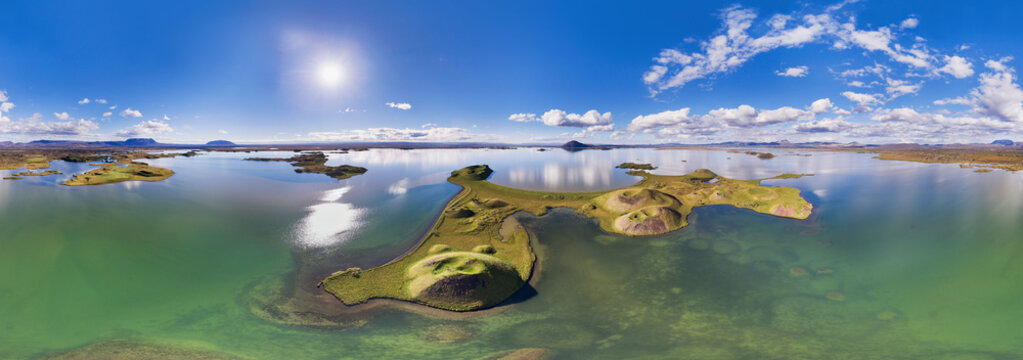 Aerial view of green islands with pseudocraters in mirroring lake under the bright sun, in 360 degrees panorama, lake Myvatn, Nordurland Eystra, Iceland.