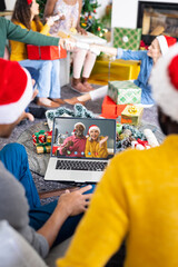 Diverse group of friends having christmas video call with senior diverse couple