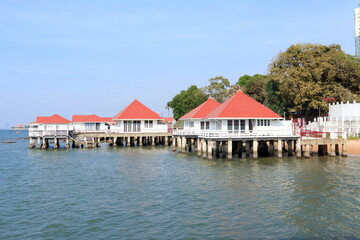 Thai traditional wood house group on cement pole in sea beside beach and blue sky in Chonburi province in Thailand.