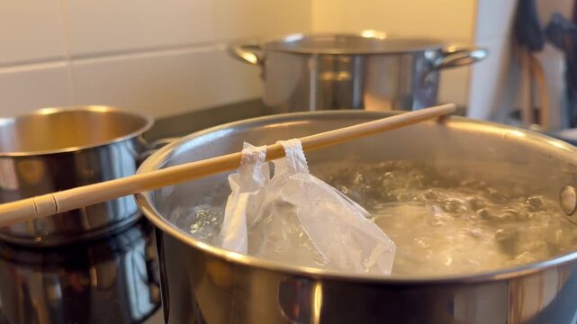 A pot of boiling water with a wooden stick in it. The pot is on a stove