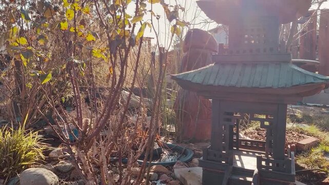 A small garden with a bird bath and a chinese pagoda. The birdhouse is on a stone platform
