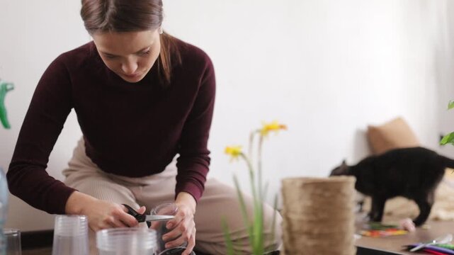A woman is transplanting flowers into the ground at home