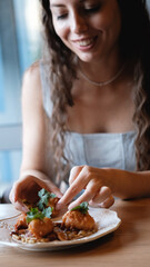 A beautiful girl eats food with her hands with gusto in a restaurant