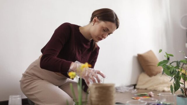 A woman is transplanting flowers into the ground at home