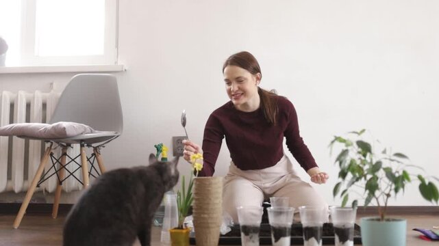A woman is transplanting flowers into the ground at home