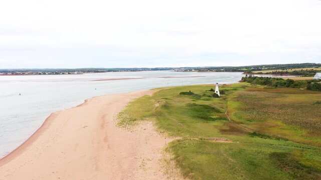 Aerial drone footage of the beautiful beach in Summerside, Prince Edward Island PEI in Canada showing the light house near the beach front and ocean on a sunny day in the autumn time