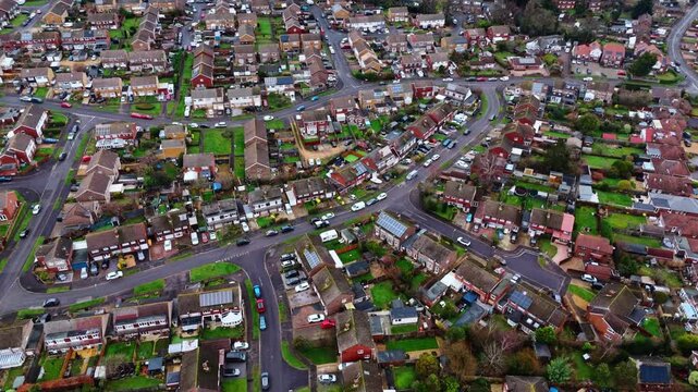 aerial panning drone shot over a suburban neighbourhood in Southampton, Hampshire named Hedge end. Shot on a quiet sunset on a cloudy winters day with many houses, fields and cars on the roads below