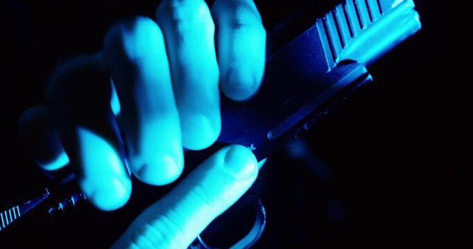 Cinematic close-up of a hand loading a pistol under blue light, symbolizing danger, tension, and a high-risk situation.