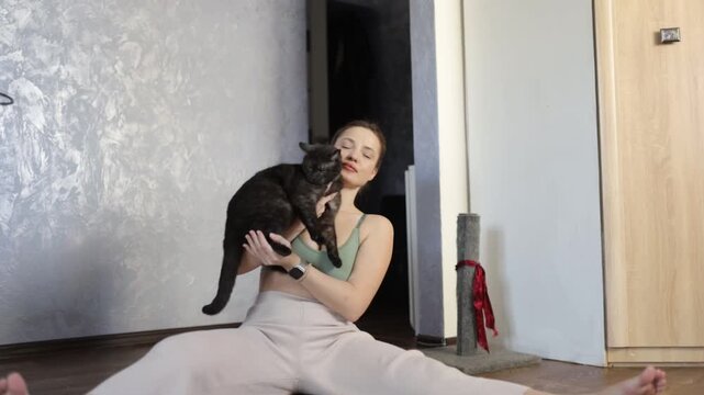 A woman with a cat doing gymnastics, yoga, and sports at home