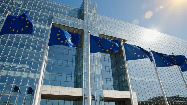 European Union flags waving in front of glass building