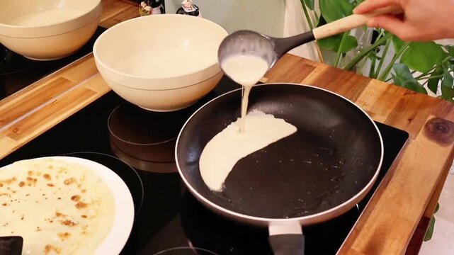  Person pouring batter into a frying pan to make pancakes.