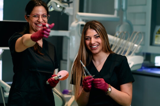 Two Friendly Dental Assistants Share a Laugh While Preparing Tools in Modern Clinic