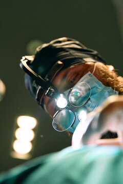Surgeon in Operating Room Using Magnifying Loupes and Headlamp During Procedure