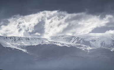 A dramatic landscape panorama in the mountains of Tajikistan in the Pamirs, the Tien Shan mountain range with rocks, snow, and glaciers in cloudy weather, a high-altitude landscape for Background