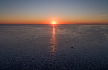 A boat is sailing in the Mediterranean Sea at sunset.
