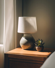 Bedroom nightstand surface with lamp base and small plant accent with right copy space pre
