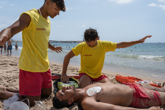 Lifeguards performing cpr with defibrillator on beach