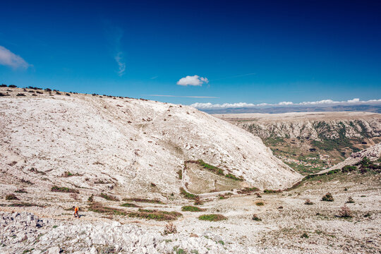 View of the stark, sun-drenched landscape with rocky textures and sparse vegetation under a clear blue sky, creating a sense of isolation, Ba&Aring;&iexcl;ka, Croatia.