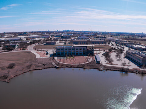 Aerial view of a tranquil lake reflecting the sky, contrasting with the modern architecture and cityscape on the horizon, Dallas, Texas, United States.