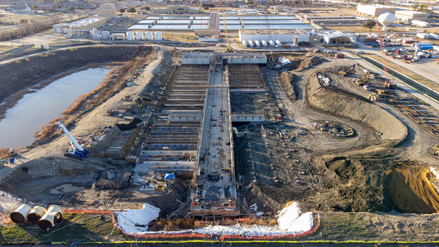 Aerial view of a construction site with heavy machinery and a nearby water treatment plant, Dallas, Texas, United States.