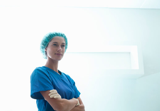 Confident female surgeon standing with arms crossed in intensive care unit at hospital