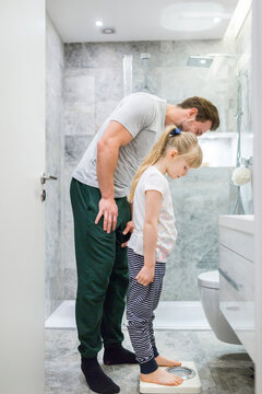 Father and daughter checking weight on bathroom scales