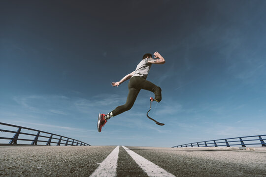 Disabled athlete with leg prosthesis exercising on a road