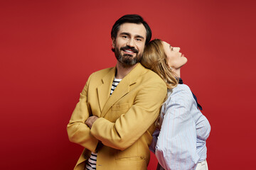 Obraz premium Stylish couple embracing love and fashion against a vibrant red backdrop in a joyful moment