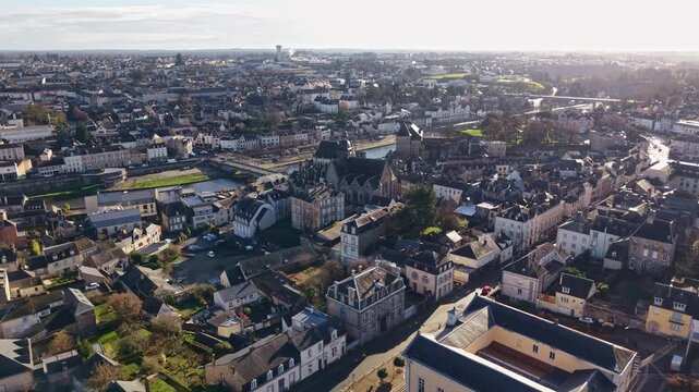 Historic town center and Basilica of Notre-Dame-des-Miracles on Mayenne river in Mayenne, France. Aerial drone forward