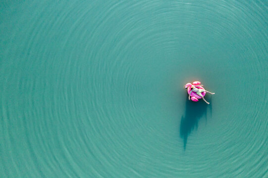 Young man with flamingo pool float on the lake