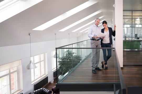 Colleagues standing in modern office, discussing documents