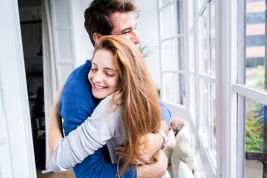 Happy affectionate couple hugging at the window at home