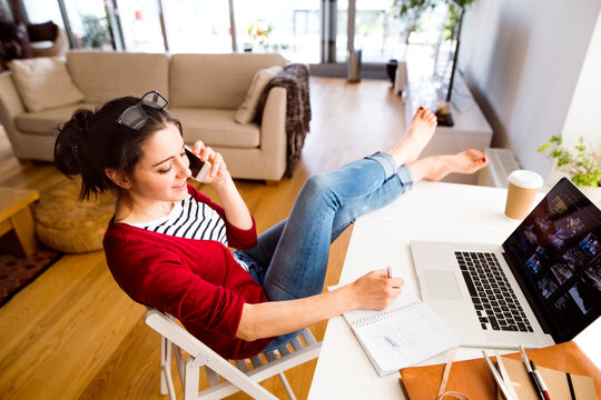 Smiling woman on the phone working at desk at home