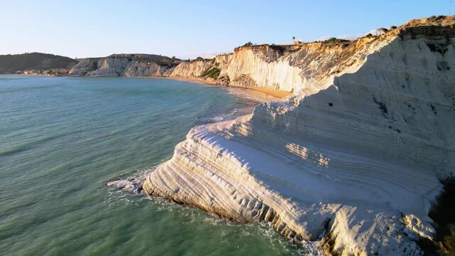 Experience the stunning Scala dei Turchi in Sicily, where majestic white cliffs meet the turquoise sea under a warm sunset. A perfect escape for travelers seeking natural beauty.