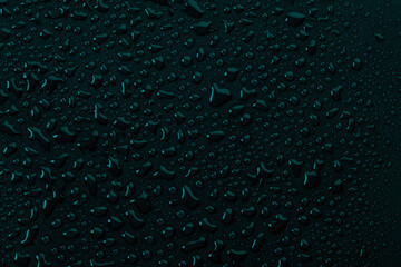 Close-up view of water droplets on a dark surface after rain at night in an urban setting