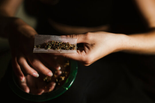 Young woman rolling a joint at home