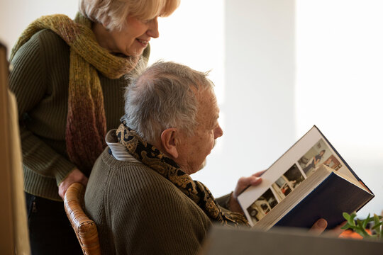 Senior couple looking at photo album surrounded by cardboard boxes in an empty room