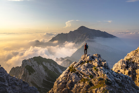 Hiker admiring awesome view while standing on mountain peak at Bergamasque Alps, Italy