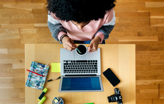 Top view of young woman working from home using laptop