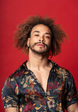 Handsome young man with curly hair standing against red background