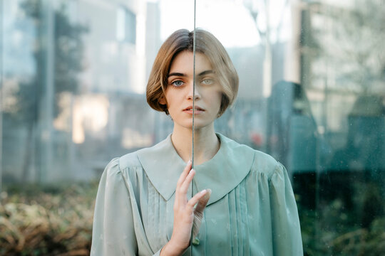 Portrait of woman with half of her face behind a glass