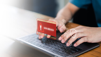 Data breach alert on laptop with hands typing for cyber security. This digital threat and hack warning concept shows a professional managing information protection and network safety. © Concept Style