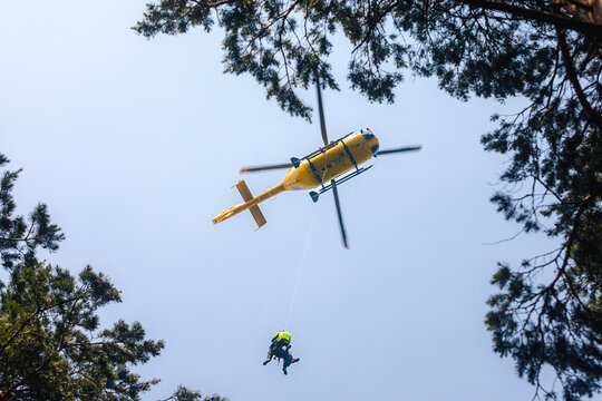 Rescuer on rope under a flying helicopter of emergency medical service. Themes rescue from difficult terrain and professional rescue.