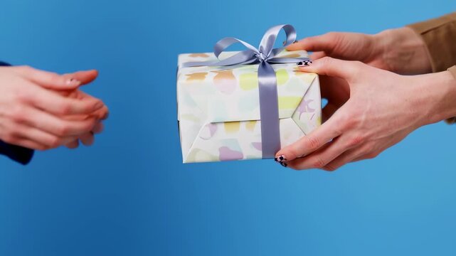 Hands exchanging a wrapped gift against a vibrant blue backdrop, symbolizing generosity