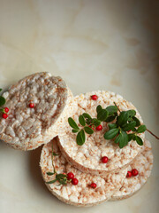 Rice cakes stacked with fresh lingonberries on light background, minimal healthy food concept.