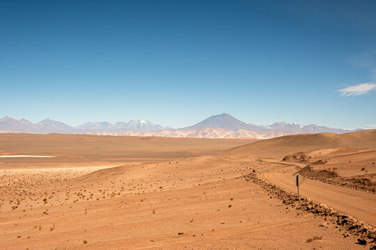 Gran valle en el desierto con volcanes nevados en el horizonte