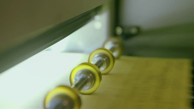 Close-up of rollers and paper in a printing or manufacturing machine