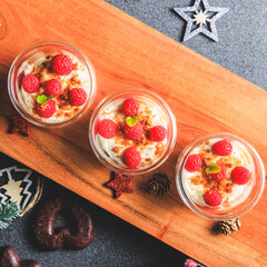Verrine of crushed speculoos, mascarpone and raspberries on a gray background decorated for Christmas