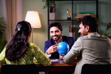 Young Indian husband and wife planning international vacation with travel consultant